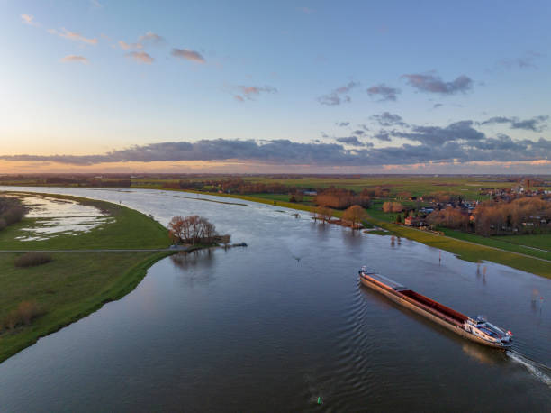 istock Freight ship sailing on the river IJssel with high water on the floodplains 1458756111