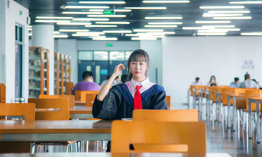 A girl in a bachelor's gown in the library