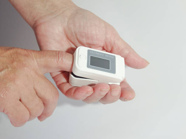 istock Woman using modern fingertip pulse oximeter on light background, closeup. Woman Uses Pulse Oximeter 1458757946