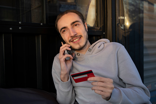 Young man making a transaction with a credit card on his phone