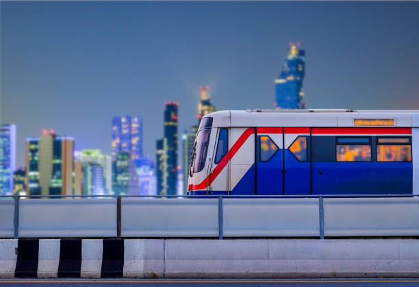 le skytrain de bangkok s’arrête sur les voies ferrées avec un arrière-plan flou de la ville sur la scène nocturne et l’espace de copie - sky city urban scene blue photos et images de collection