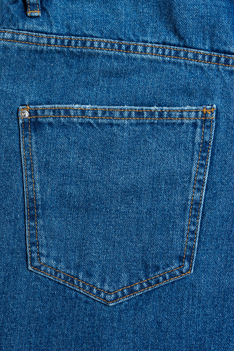 Back side and pockets of blue jeans pants close-up. Denim background, texture, wallpaper, fashion concept. Design detail, button and seams.