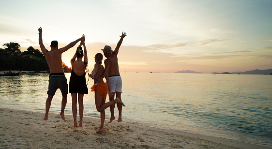 Group of friends having fun on the beach during sunset, having fun and jumping. Young people enjoying summer vacation. Travelers. Tourism.
