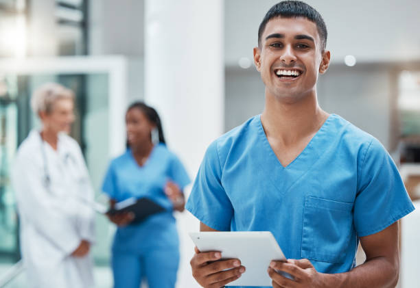 tablet, healthcare and medicine with a man nurse doing research in a hospital for health or treatment. medical, insurance and medicare with a young male clinic worker doing a search online - senior adult happiness computer looking at camera imagens e fotografias de stock