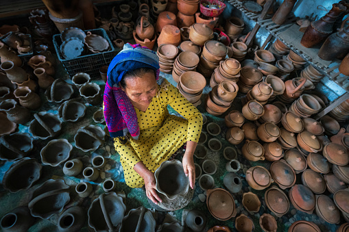 A woman is molding clay for making pottery vase in traditional pottery village Bau Truc - Phan Rang city, Ninh Thuan province, central Vietnam