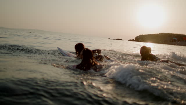 Friends running into the sea with their surfboards
