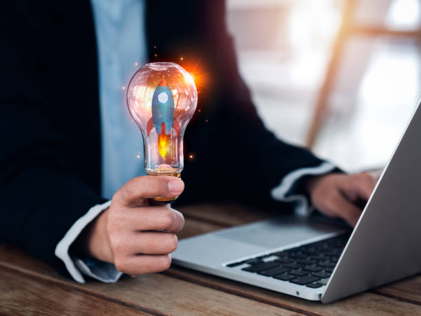istock Startup business concept. Launching up the rocket, 3d graphic in creative idea light bulb holding by businessperson hand who working with laptop computer. Creative motivation for successful business. 1458777962