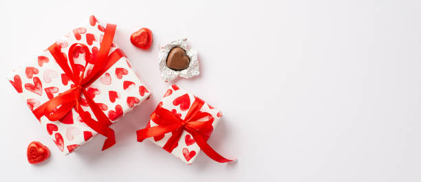 koncepcja walentynkowa. zdjęcie z góry przedstawiające pudełka z kokardkami z czerwonej wstążki i czekoladowymi cukierkami w kształcie serca na izolowanym białym tle z przestrzenią kopiowania - valentines day candy chocolate candy heart shape zdjęcia i obrazy z banku zdjęć