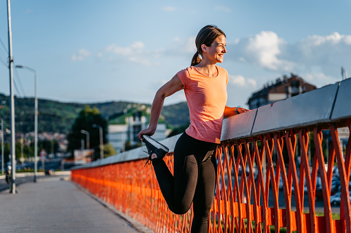 Beautiful young woman stretching on the bridge before running.