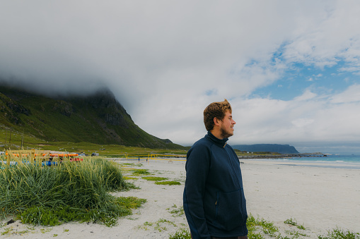 Portrait of a happy male traveler enjoying a summer time at the scenic mountain beach on Lofoten, Norway