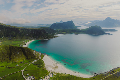 High-angle photo of the scenic landscape with the road, turquoise-colored white sand beach and the mountain peaks on Lofoten, Nordland, Northern Norway