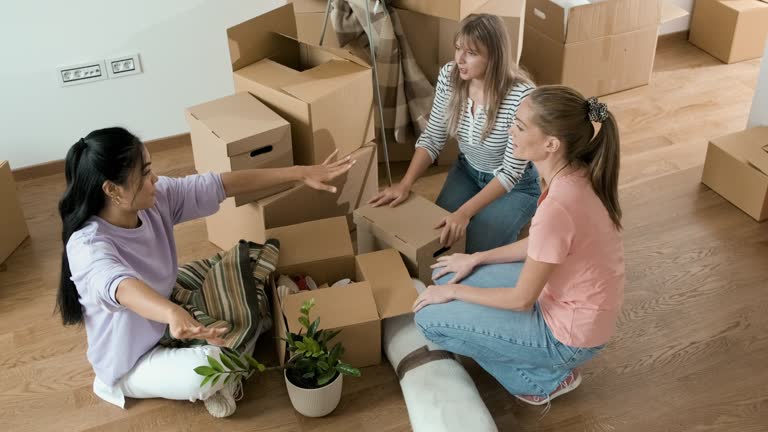 Three female friends unpacking boxes in new home.