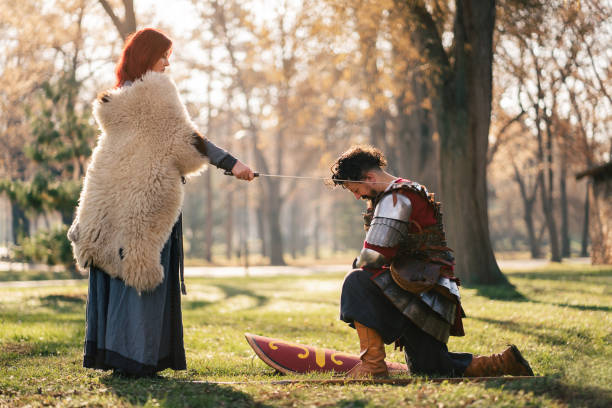 Queen using sword for an initiation ceremony, while proclaiming the medieval warrior a knight