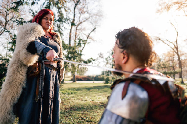 istock Queen using sword for an initiation ceremony, while proclaiming the medieval warrior a knight 1458783758