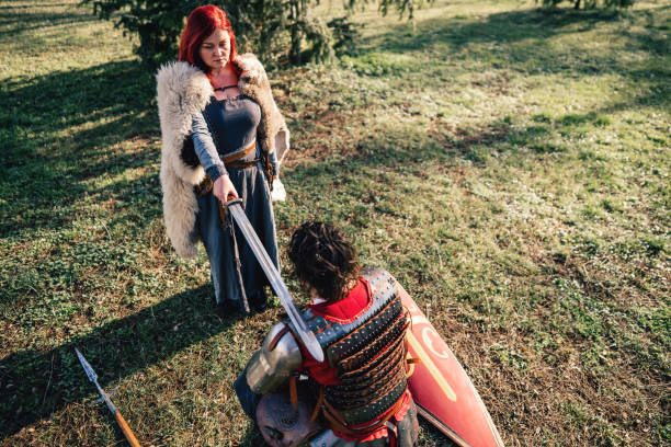 istock Queen using sword for an initiation ceremony, while proclaiming the medieval warrior a knight 1458783838