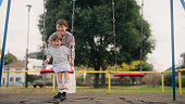 Mother pushing her small daughter on swing in public park