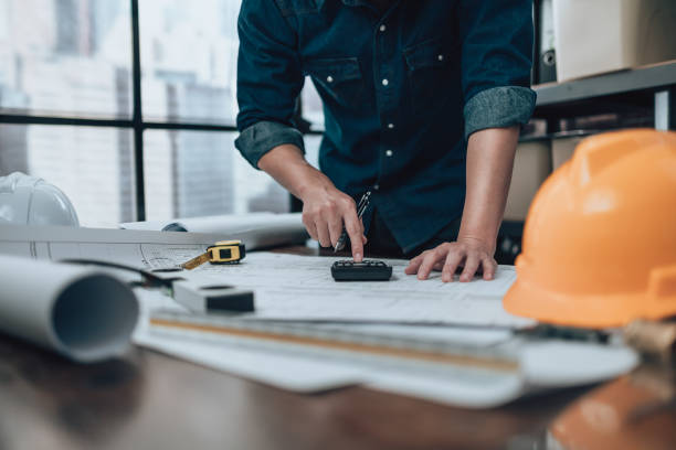 istock Engineering working with drawings inspection and press calculator on the office desk and triangle ruler, safety glasses, compass, vernier caliper on Blueprint. Engineer, Architect, Industry and factory concept. 1458792267