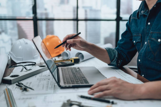 istock Engineering working with drawings inspection on laptop  in the office and Calculator, triangle ruler, safety glasses, compass, vernier caliper on Blueprint. Engineer, Architect, Industry and factory concept. 1458794688