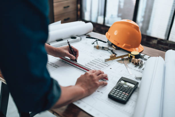 istock Engineering working with drawings inspection and writing on the office desk and Calculator, triangle ruler, safety glasses, compass, vernier caliper on Blueprint. Engineer, Architect, Industry and factory concept. 1458795086