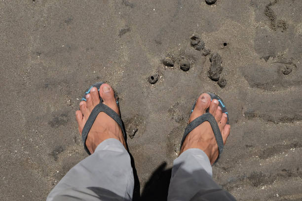 istock Man's feet on wavy beach sand during daytime, summer travel background 1458795433