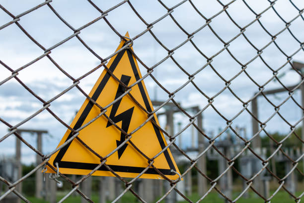 istock Yellow triangle with lightning behind metal mesh fence, high voltage warning sign 1458795915