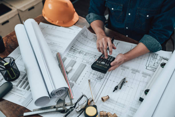 istock Engineering working with drawings inspection and press calculator on the office desk and triangle ruler, safety glasses, compass, vernier caliper on Blueprint. Engineer, Architect, Industry and factory concept. 1458796791