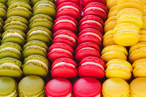 Close up macro color image depicting colorful fresh macaroons for sale at a food market.