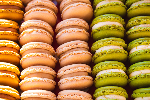 Close up macro color image depicting colorful fresh macaroons for sale at a food market.