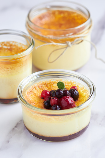 egg custard in glass jars with red fruits on top