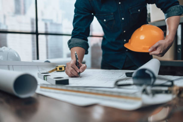 istock Engineering working with drawings inspection on the office desk and Calculator, triangle ruler, safety glasses, compass, vernier caliper on Blueprint. Engineer, Architect, Industry and factory concept. 1458800759