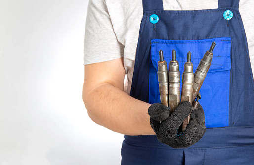 Car mechanic holds fuel car injectors in his hand. The concept of replacing and tuning the fuel system of a car at a car service. Close-up. Copy space for text