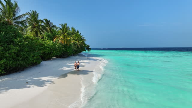 Aerial view of young couple walking on tropical beach
