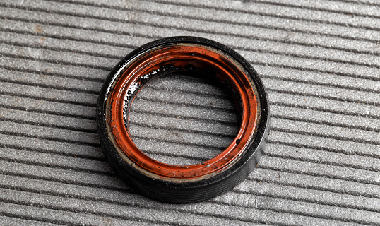 Camshaft oil seal in a car engine on a gray background