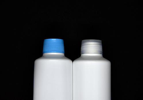 Plastic white vials on a black background. Plastic bottles. White plastic containers.
