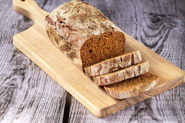 istock Loaf of dark bread on a board with cut pieces 1458806485