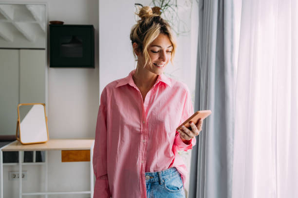 A Happy Beautiful Businesswoman Watching Funny Videos On Social Networks On Her Mobile Phone While Relaxing At Home stock photo