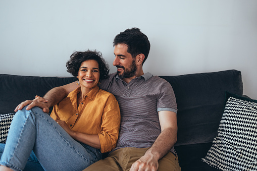 A portrait of a pretty Latin-American woman and her smiling Caucasian boyfriend relaxing at home.