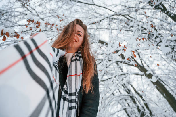 View from below. Beautiful young woman is outdoors in the winter forest.