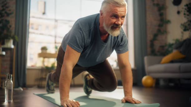 istock Strong Athletic Fit Middle Aged Man Doing Mountain Climber Exercises During Morning Workout at Home in Bright Apartment. Healthy Lifestyle, Fitness, Recreation, Wellbeing and Retirement. 1458816640