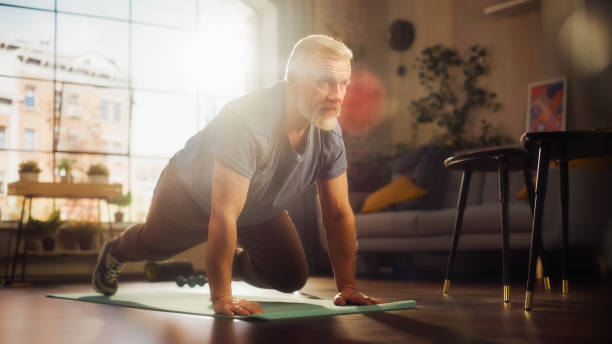 istock Strong Athletic Fit Middle Aged Man Doing Mountain Climber Exercises During Morning Workout at Home in Sunny Apartment. Healthy Lifestyle, Fitness, Recreation, Wellbeing and Retirement. 1458816677