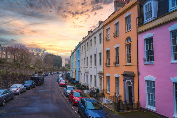 Traditional English urban street at sunset; cars parked along road