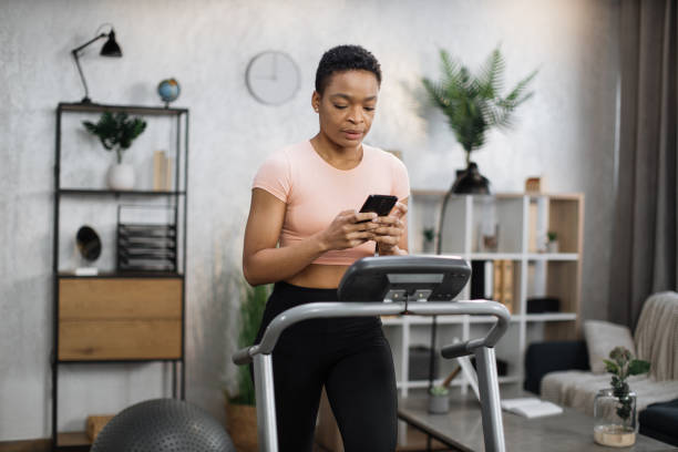 istock Attractive young sports african woman using phone while working out 1458819119