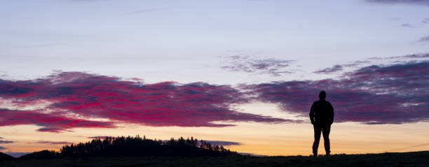 istock Man on mountain and red clouds at dawn. 1458819331