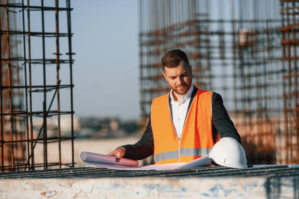 istock Man is working on the construction site at daytime. Reading the plan 1458820274