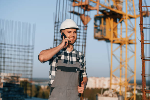 istock Beautiful man is working on the construction site at daytime and talking by phone 1458821106