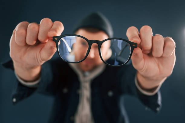 istock Funny guy playing with glasses. Handsome man is in the studio against blue background 1458825000