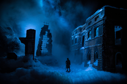War apocalypse concept. Snow covered ruined city destroyed by war. Refugees and civilians silhouettes on dark. Creative artwork decoration in dark. Selective focus