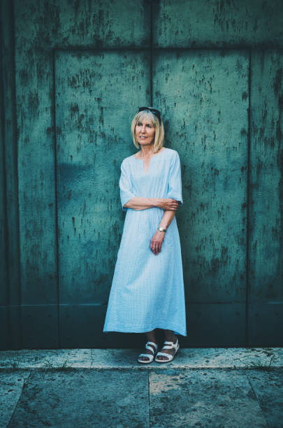 Woman in a light blue dress standing in the shade at Siena, Tuscany, Italy.