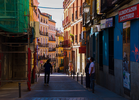 People walking in the morning in the narrow colorful streets of Madrid with residential buildings on either side