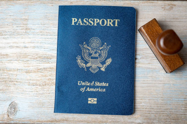 istock US passport and stamp on wooden background. Safe journey with necessary documentation. Top view. Copy space 1458830784